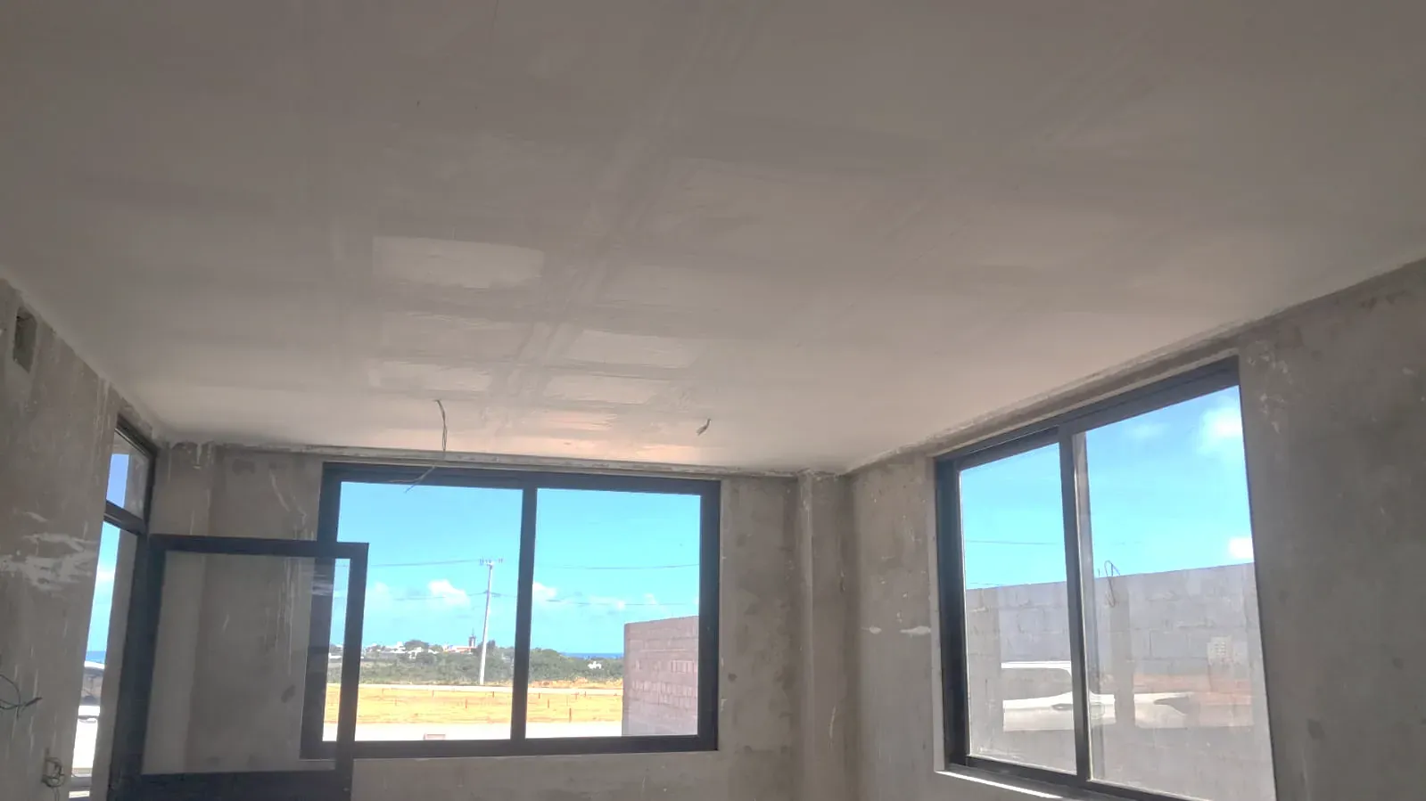 Uma das salas da portaria, com o forro de gesso fechado e as esquadrias instaladas.