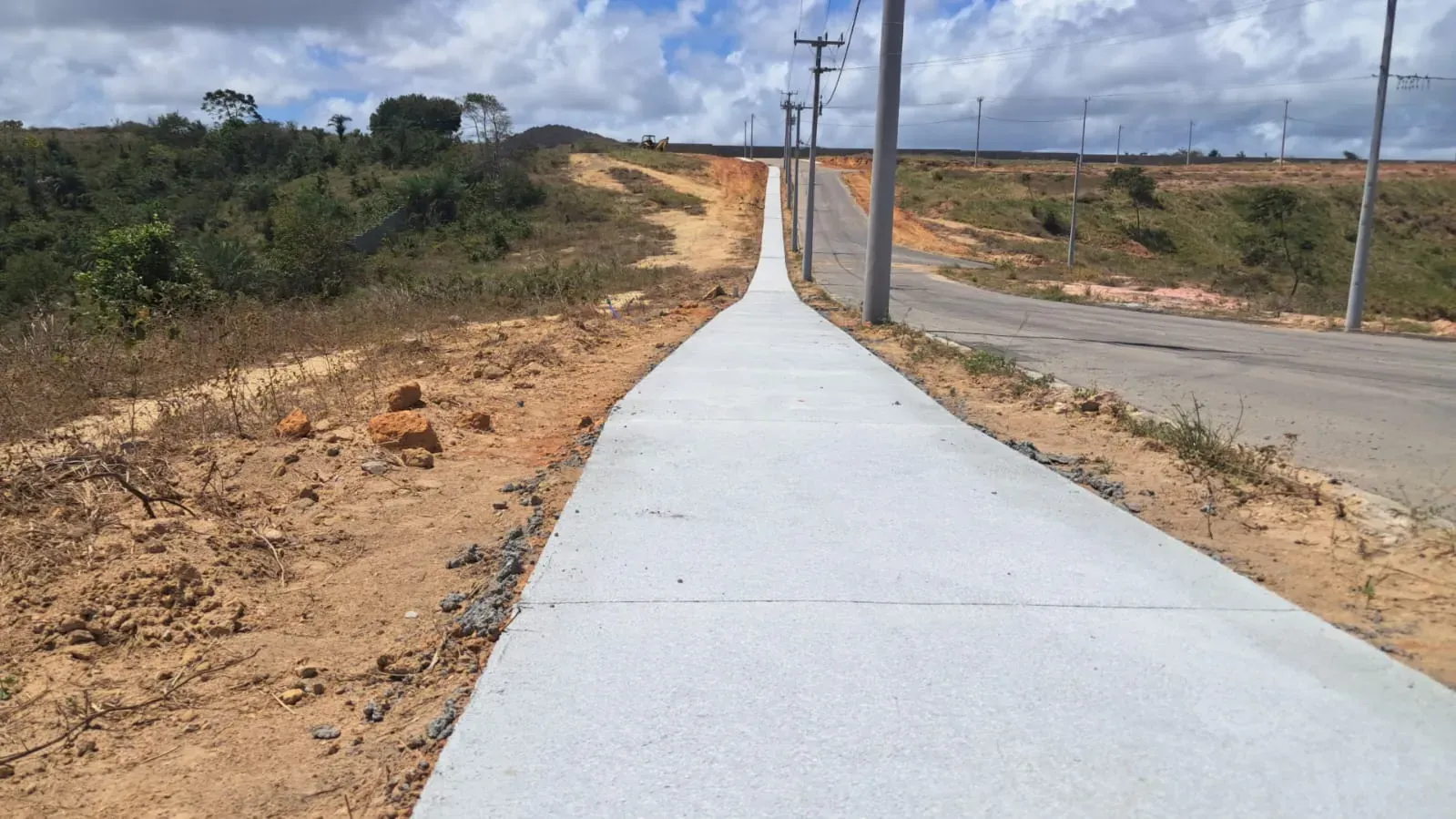 A calçada nova acompanha a via em linha reta até o alto do terreno.
