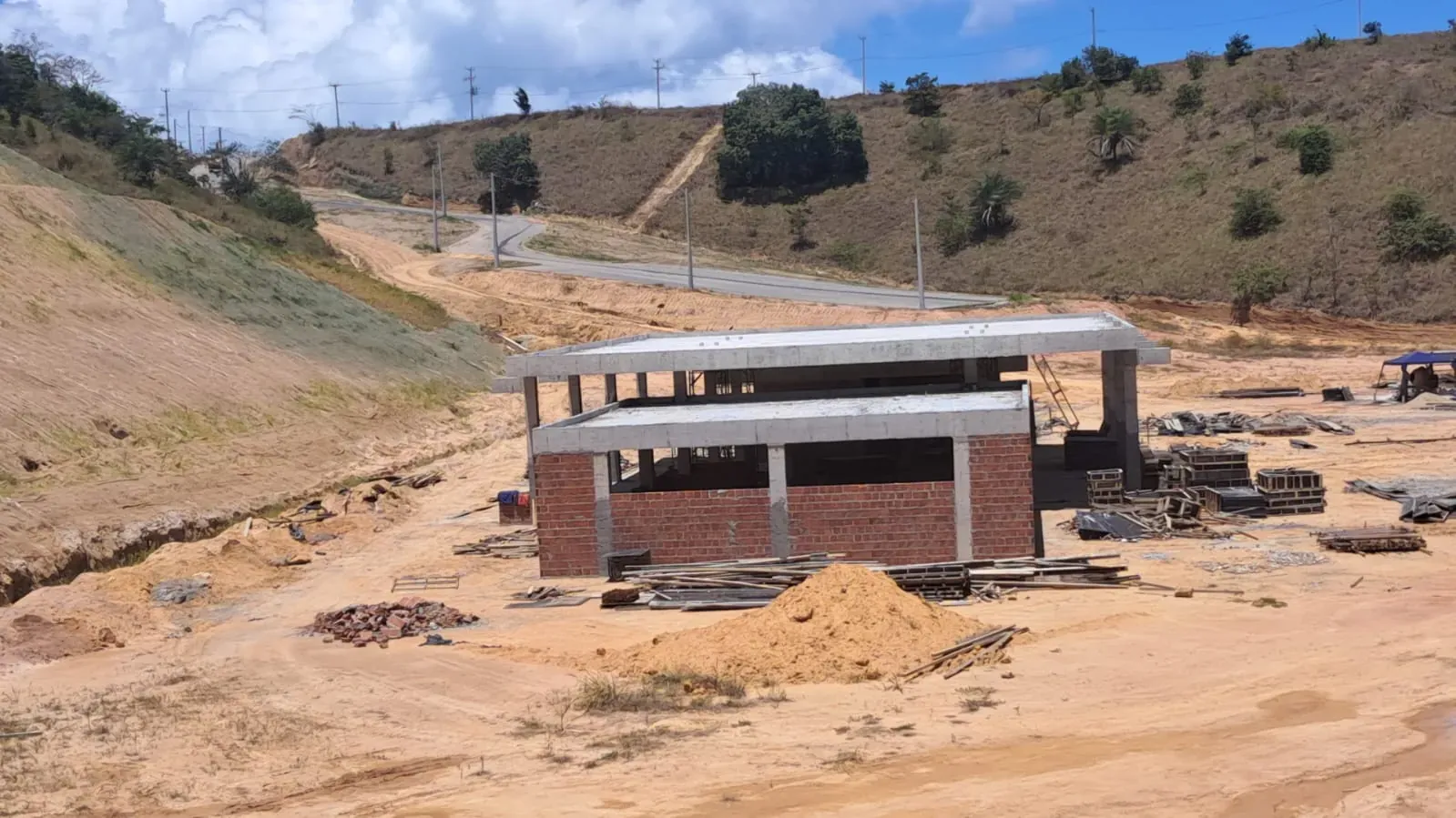 O clube visto do alto, com a alvenaria de tijolo fechando o térreo entre os pilares e o talude já semeado à esquerda.