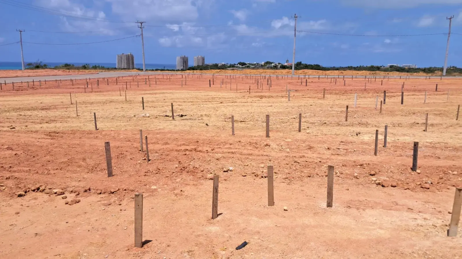 Estacas marcando no terreno os passeios da praça principal do Tramonto, com o mar ao fundo