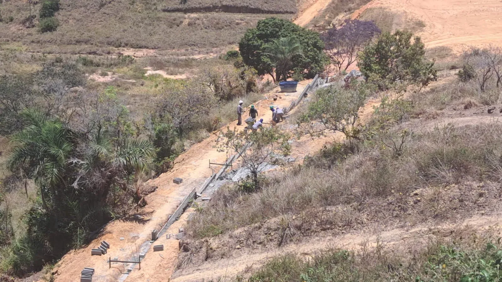 O muro perimetral visto do alto da encosta, com os blocos de concreto distribuídos ao longo do traçado.